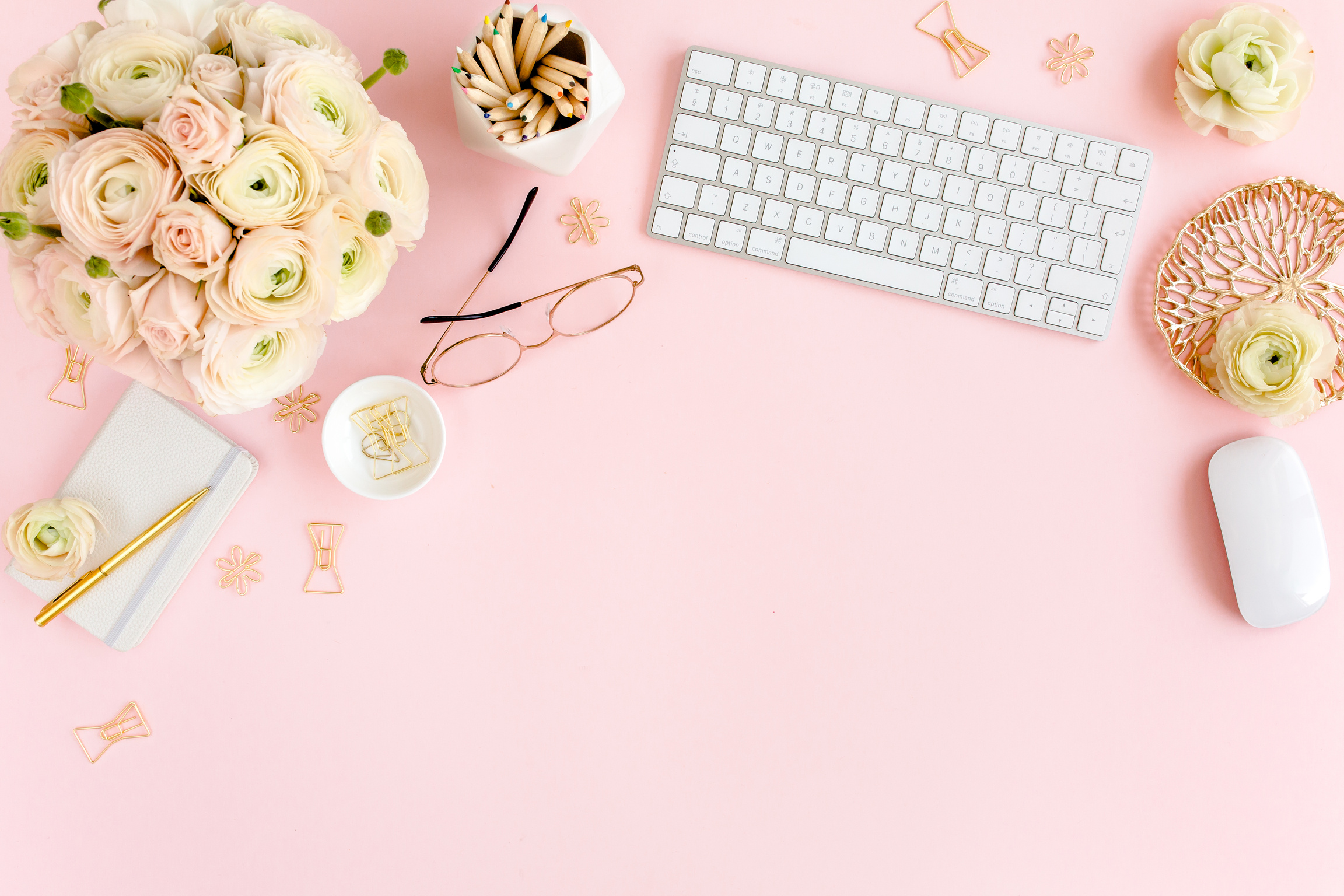 Stylized, pink women's home office desk. Workspace with computer, bouquet ranunculus and roses, clipboard, feminine golden fashion accessories isolated on pink background. Flat lay. Top view.